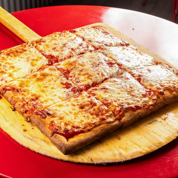 Al Forno's square-cut cheese pizza with crispy crust, served on a wooden peel.