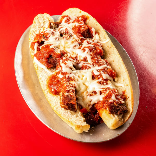 Al Forno's meatball sub, topped with marinara sauce and melted mozzarella cheese on a metal plate.