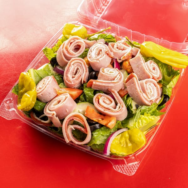 Al Forno's antipasto salad with rolled meats, lettuce, tomatoes, olives, and peppers in a plastic container.